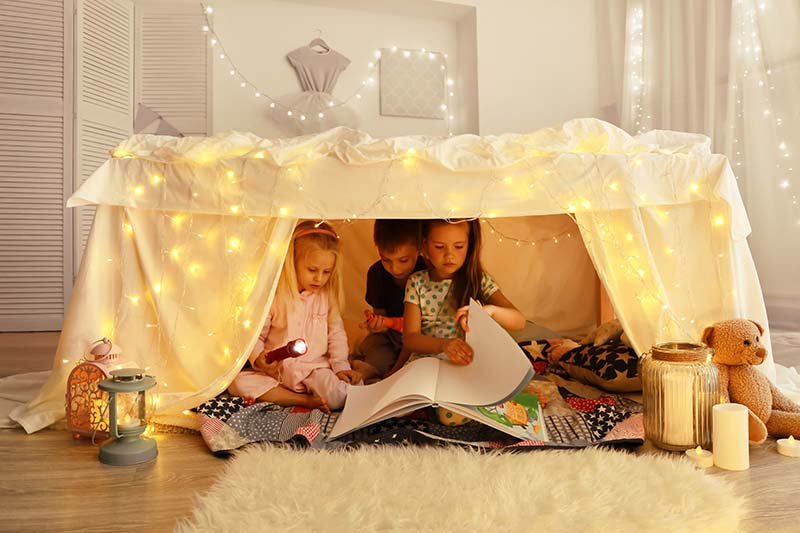 cute little children reading book in hovel at home