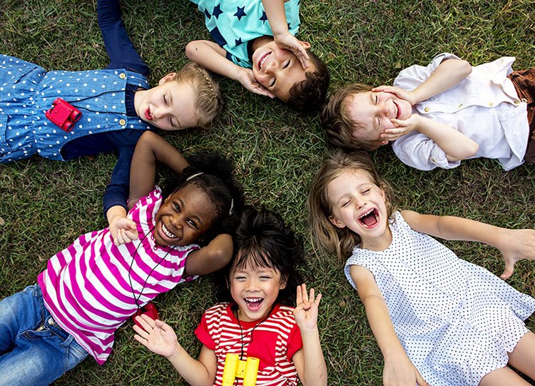 group of kindergarten kids lying on the grass at park and relax